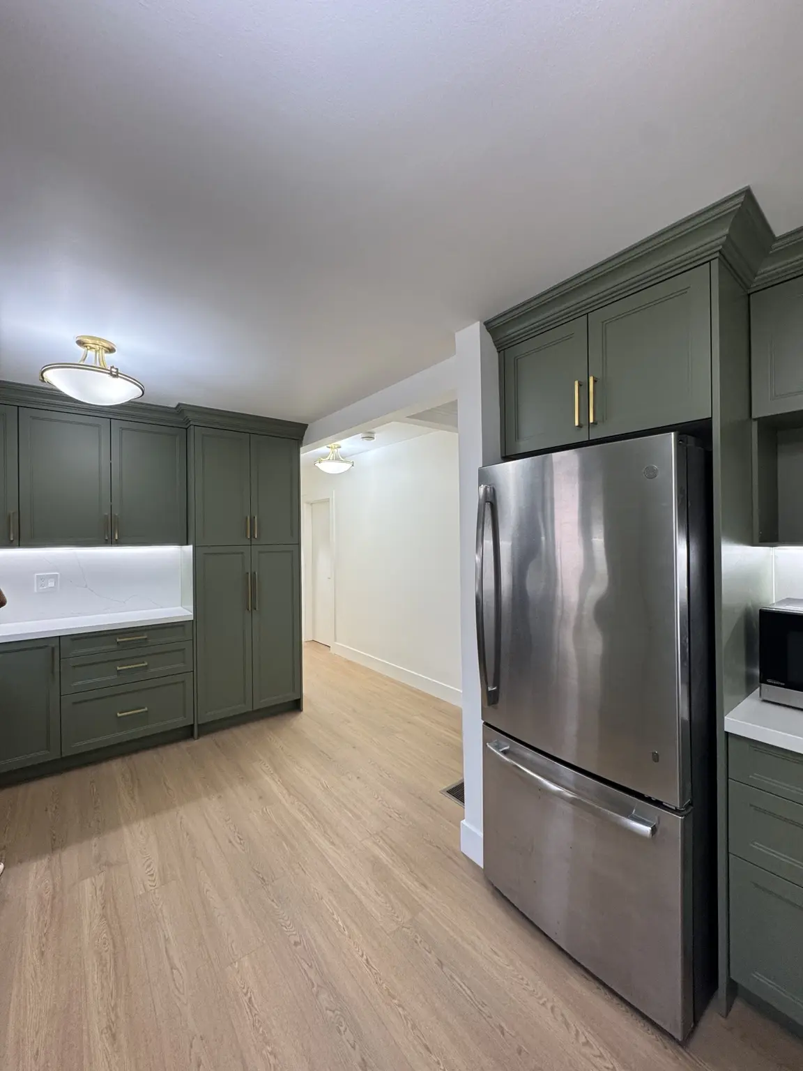 Expanded kitchen with custom sage cabinetry, stainless steel appliances and new wood-look flooring