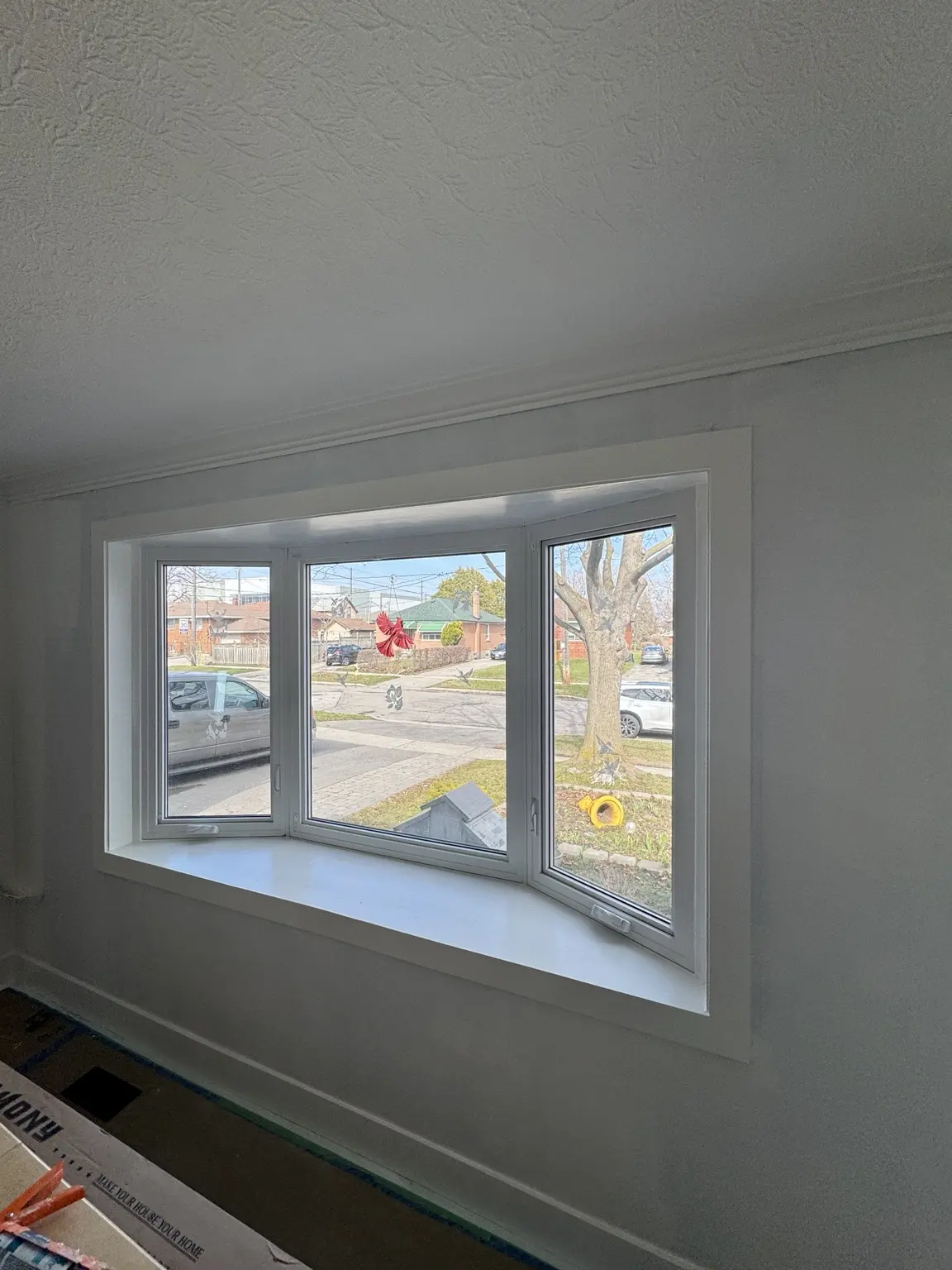 Freshly painted main-floor room with finished bay-window trim and new baseboards
