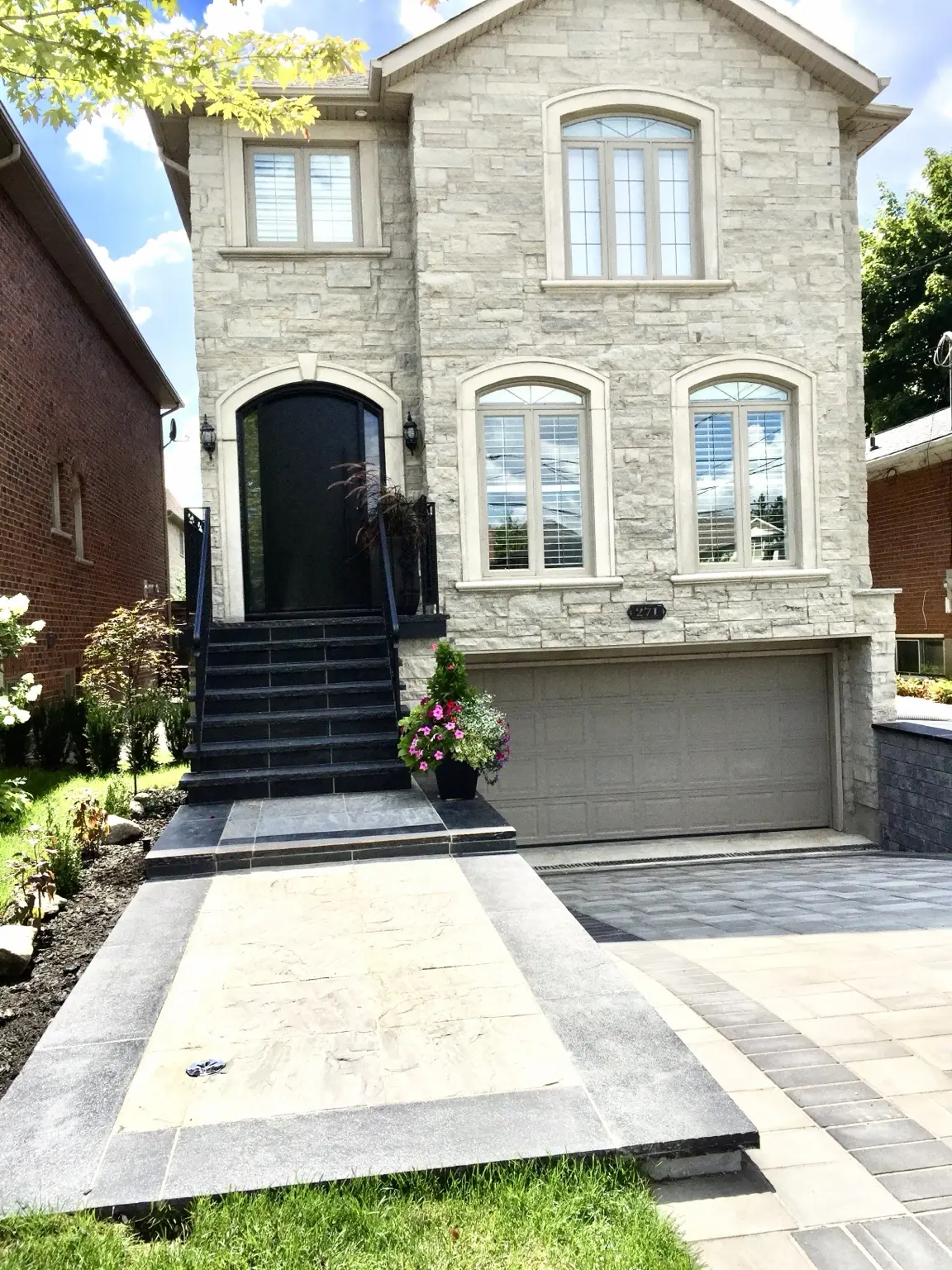 Completed stone home façade with renovated front staircase, black entrance door and coordinated walkway