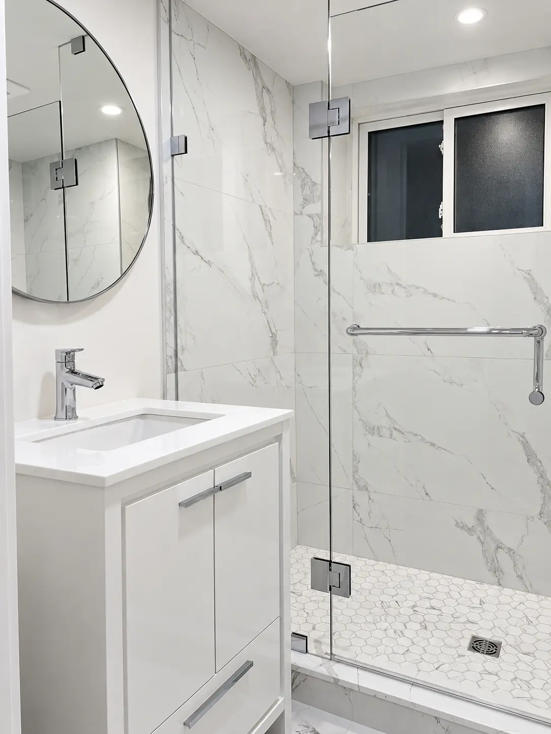Basement bathroom with glass shower, marble-look tile and white vanity