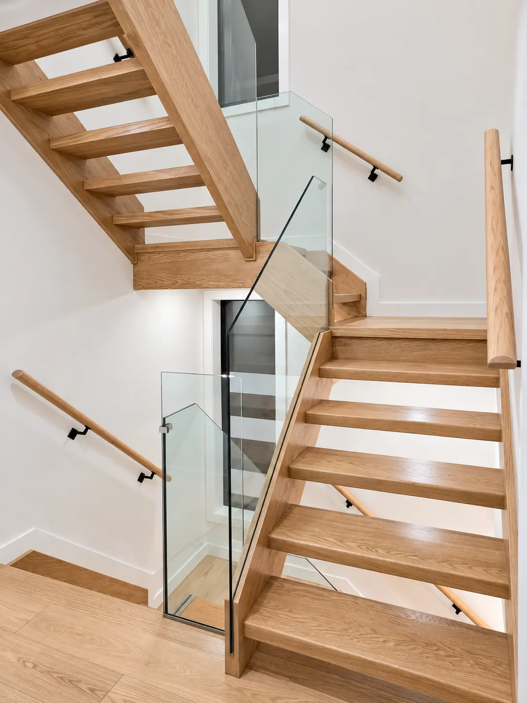 Detailed view of the open-riser oak staircase and glass guards