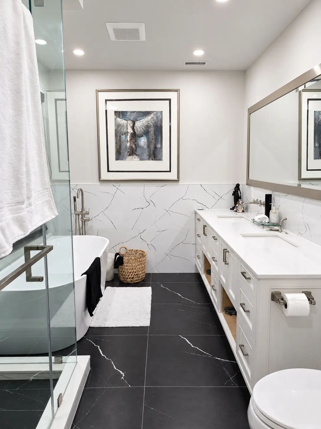 Renovated bathroom with freestanding tub, glass shower, double vanity and marble finishes