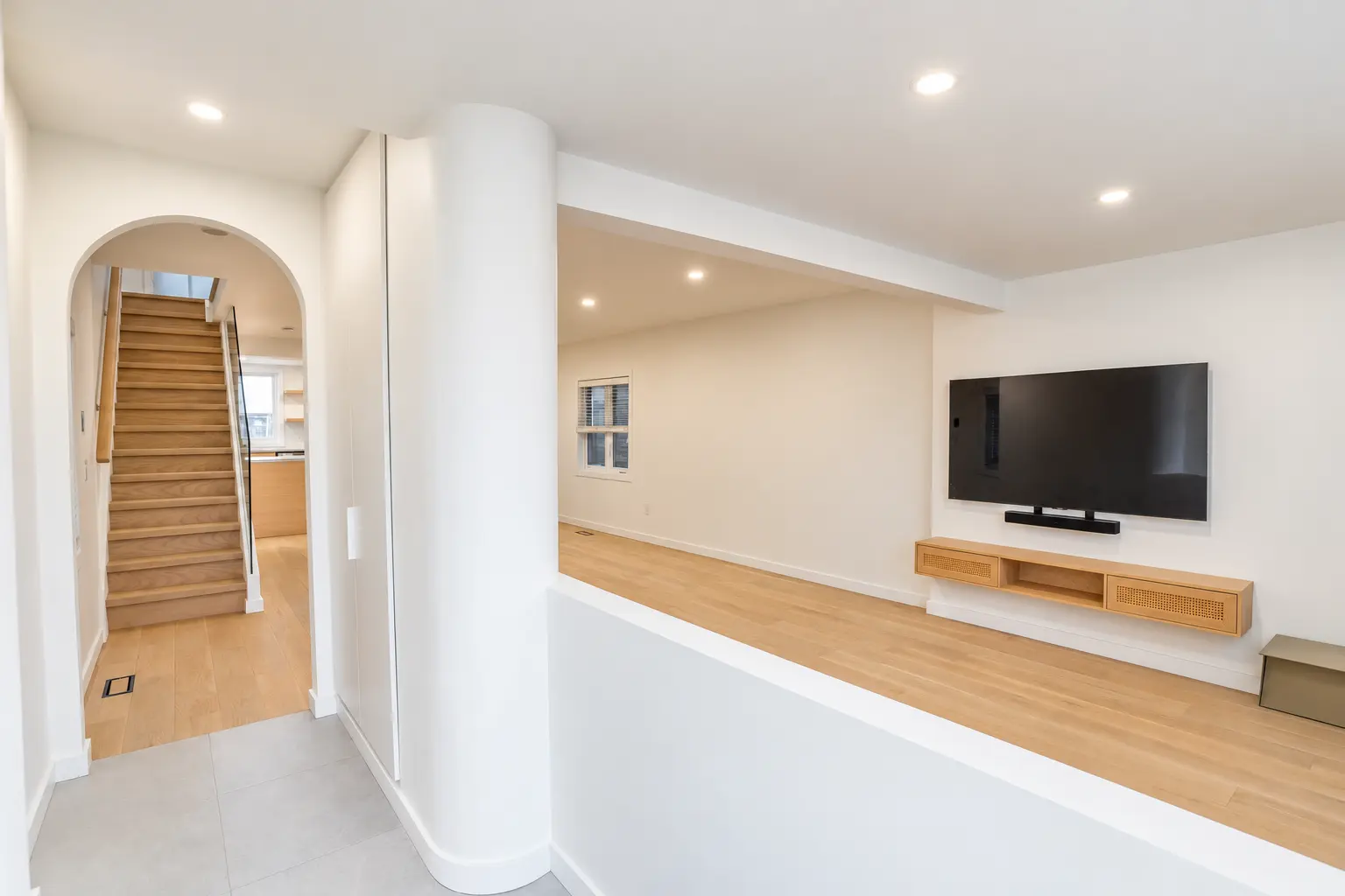 Open-concept main floor with flush structural beam, oak flooring and redesigned staircase