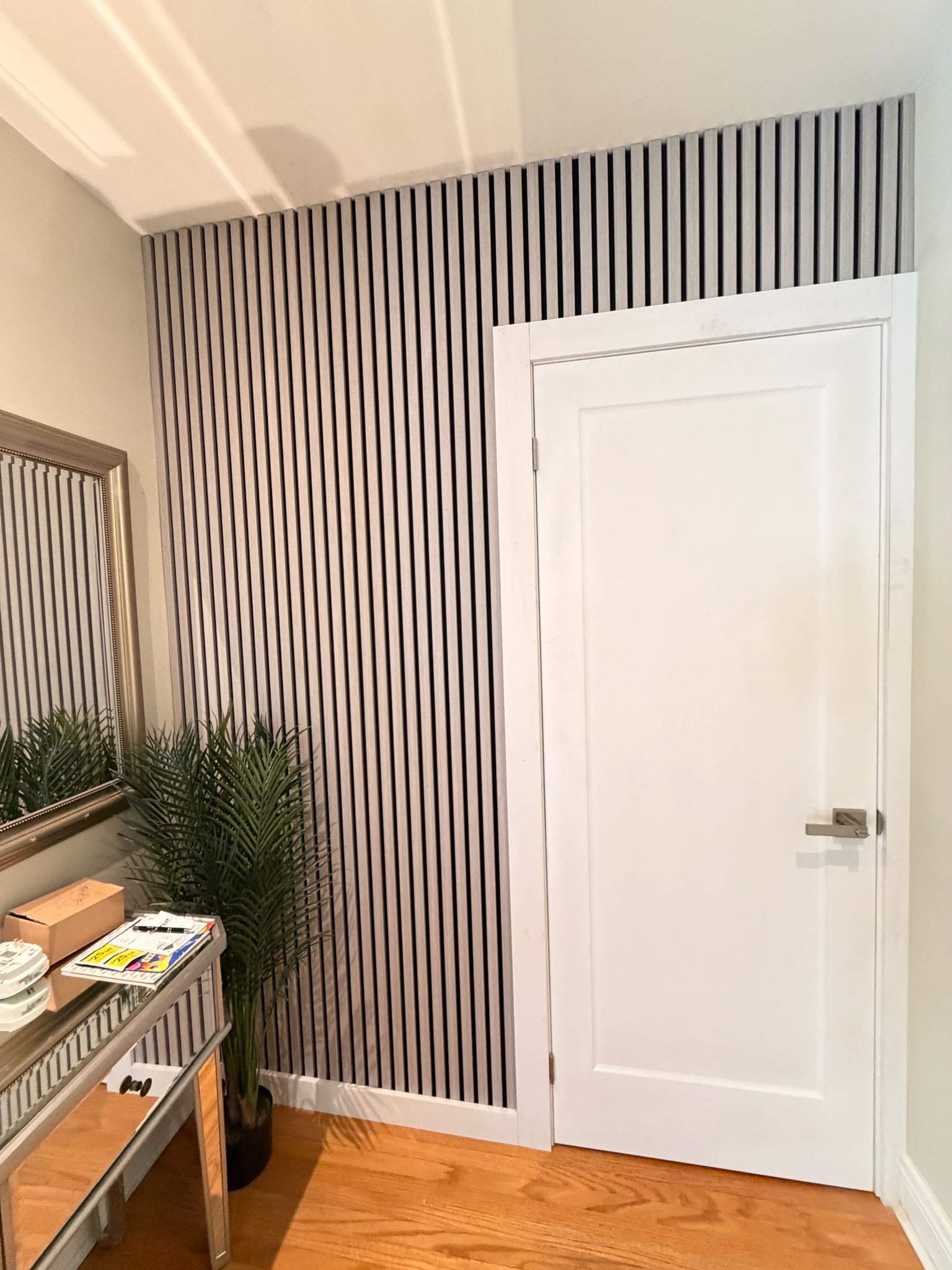 New white interior door framed by a decorative vertical slat accent wall