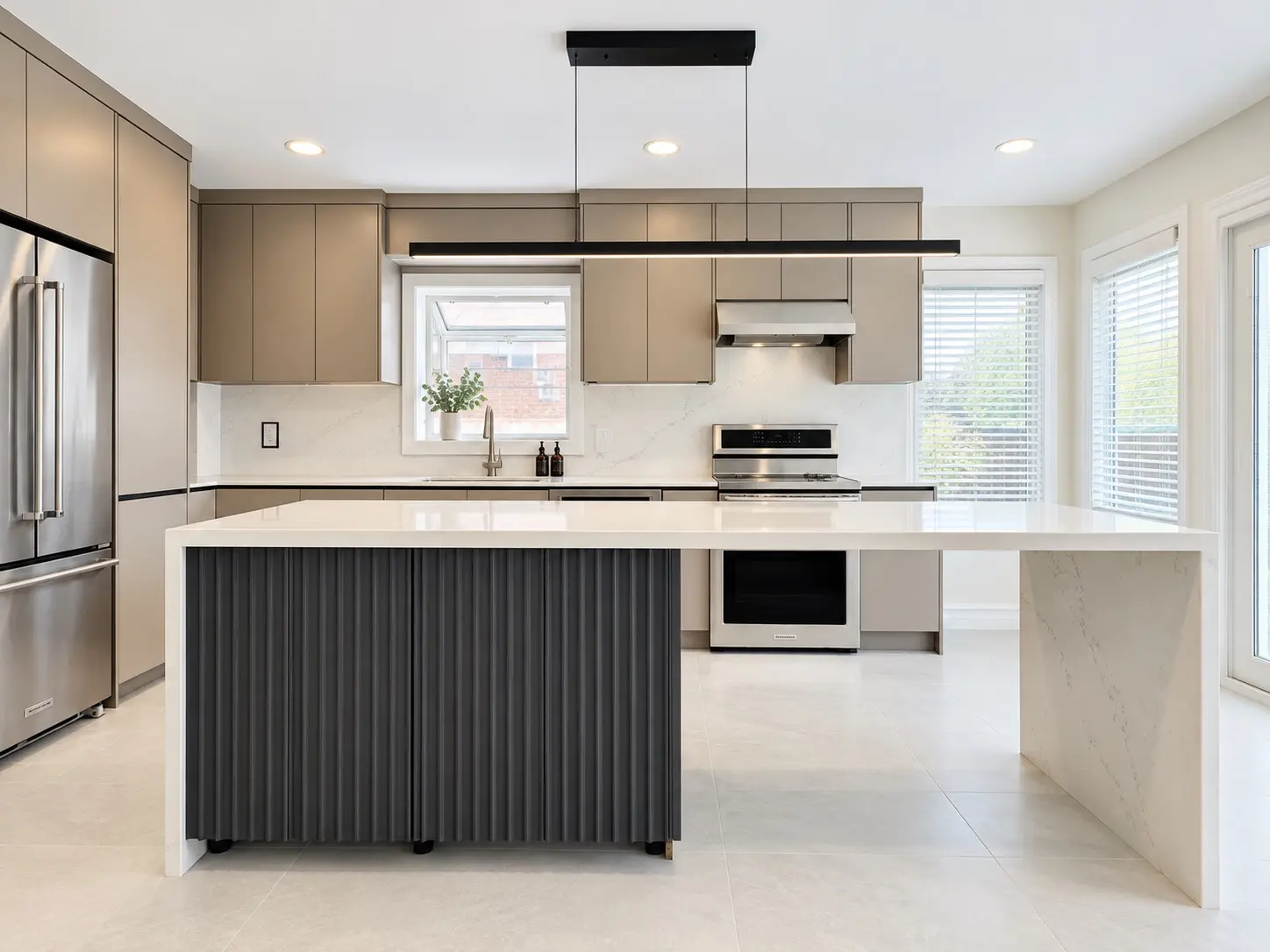 Completed modern kitchen with waterfall quartz island, custom cabinetry and linear pendant lighting