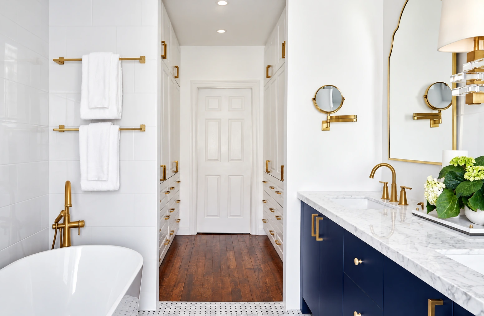 Finished bathroom with freestanding bathtub, navy vanity and white storage cabinetry