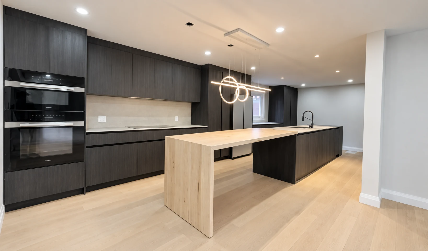 Completed contemporary Oakville kitchen with dark cabinetry, a warm wood island and wide-plank flooring